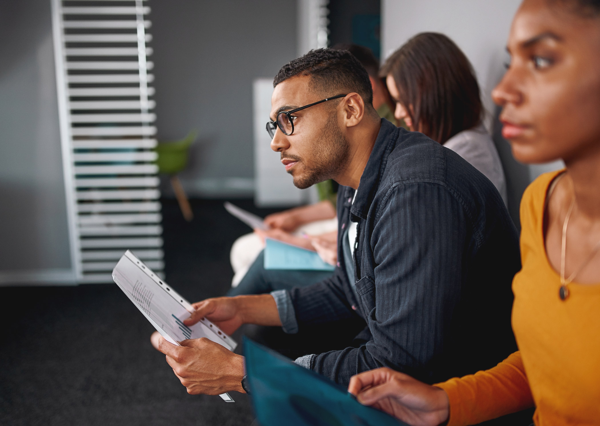 An employee sitting intently in a meeting holding paper