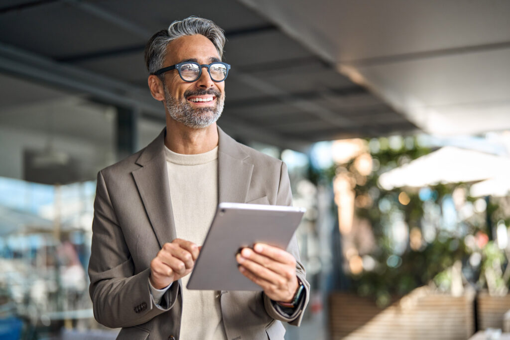 An employer holding a tablet smiling in the office